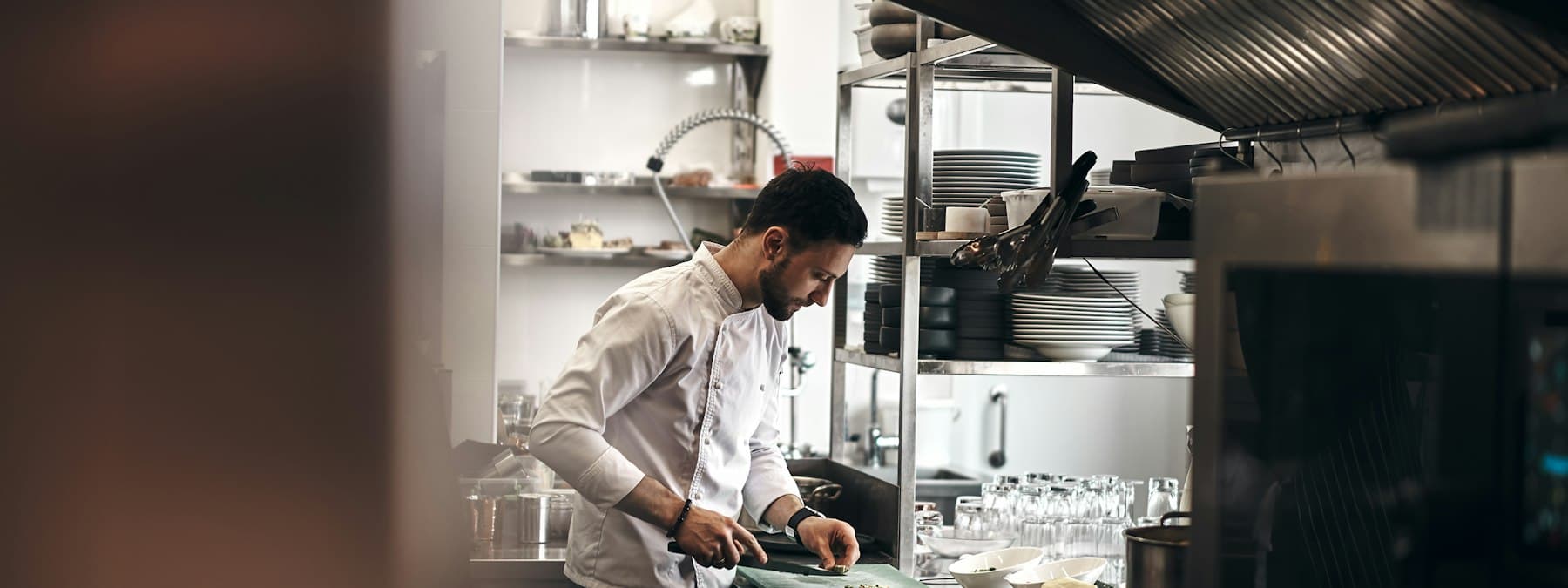 A chef plating a dish at a kitchen pass.