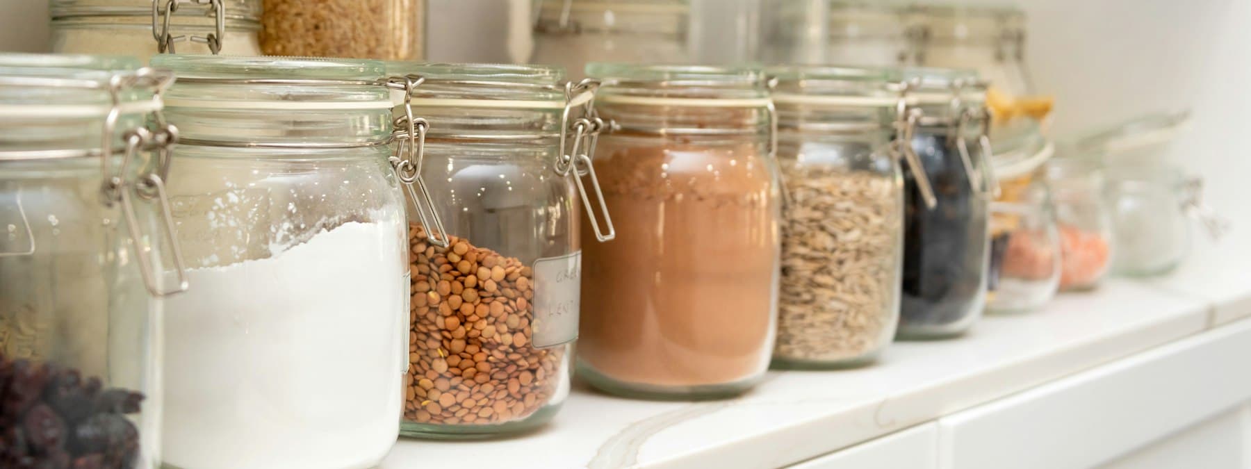 Rows of labelled jars and dry goods on pantry shelves.